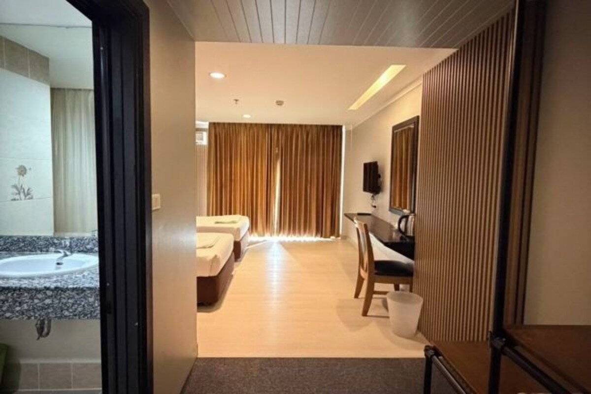 A hotel room with a bathroom, a bed, a desk, and a chair.