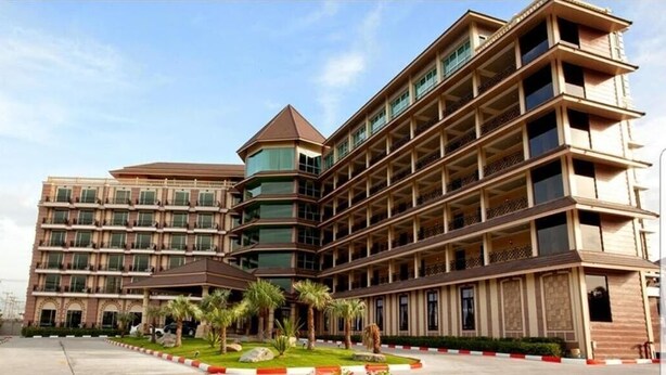 A multi-story hotel with a central courtyard, balconies, and a distinctive tower-like structure. - J & Y Lodge Hotel (Chonburi)