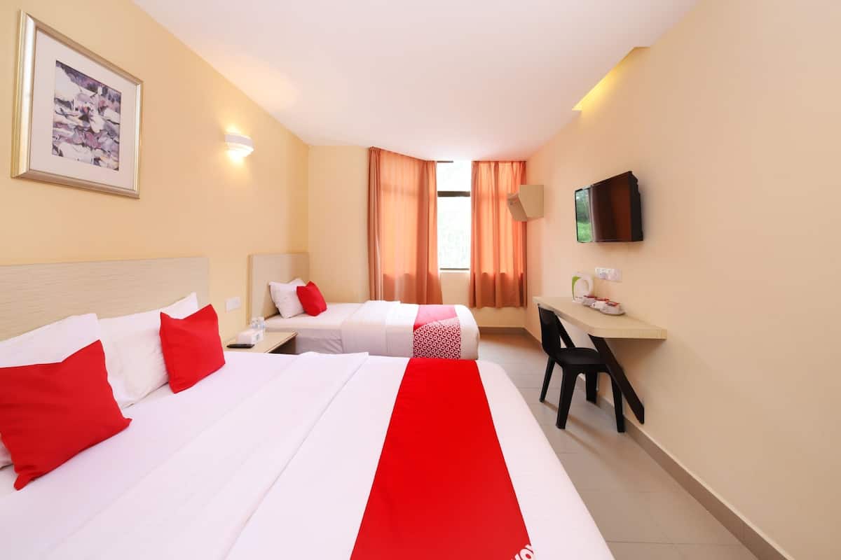 Une chambre d’hôtel avec deux lits, un bureau, une chaise, une télévision et un tableau encadré au mur.
