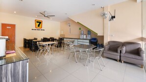 A hotel lobby with a reception desk, a dining area with tables and chairs, a sofa, and a ceiling fan. - Super OYO 635 Seven Days Hotel (Raub)