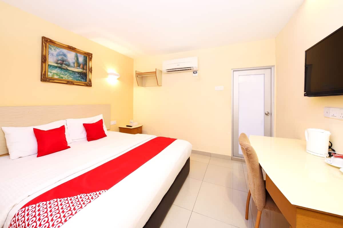Une chambre d’hôtel équipée d’un lit, d’un bureau, d’une chaise, d’un tableau, d’un climatiseur et d’un téléviseur.