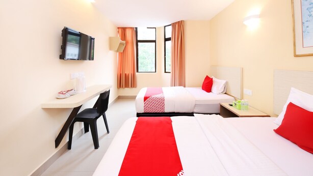 A hotel room with two beds, a desk, a chair, a TV, and a window with curtains. - Super OYO 635 Seven Days Hotel (Raub)
