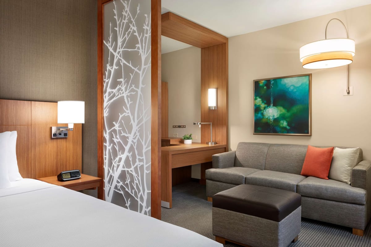 Een hotelkamer met een bed, een bureau, een bank en een groot schilderij aan de muur.
