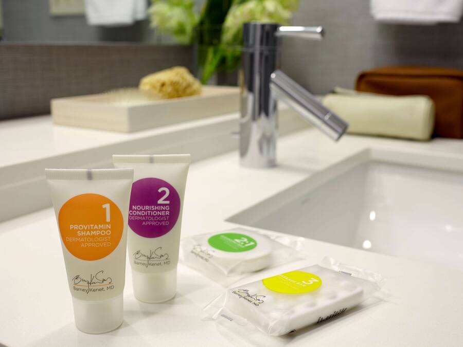 A bathroom counter with toiletries, including two tubes of Provitamin Shampoo and a bar of soap.