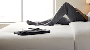 A person reclining on a bed with a notebook and pen on it.