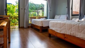 A hotel room with two beds, a wooden floor, and a balcony with curtains. - Areca Garden Bungalow (Phu Quoc)