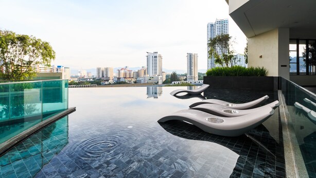 A rooftop infinity pool with modern lounge chairs, surrounded by a glass railing and a cityscape view. - J DUPION Boutique Suites by NowHere (Kuala Lumpur)