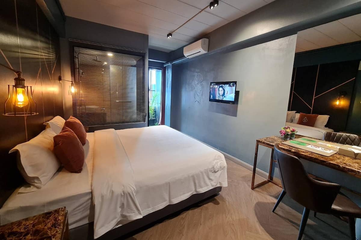 Moderni hotellihuone, jossa on suuri sänky, työpöytä tuolilla ja seinälle asennettu televisio.
