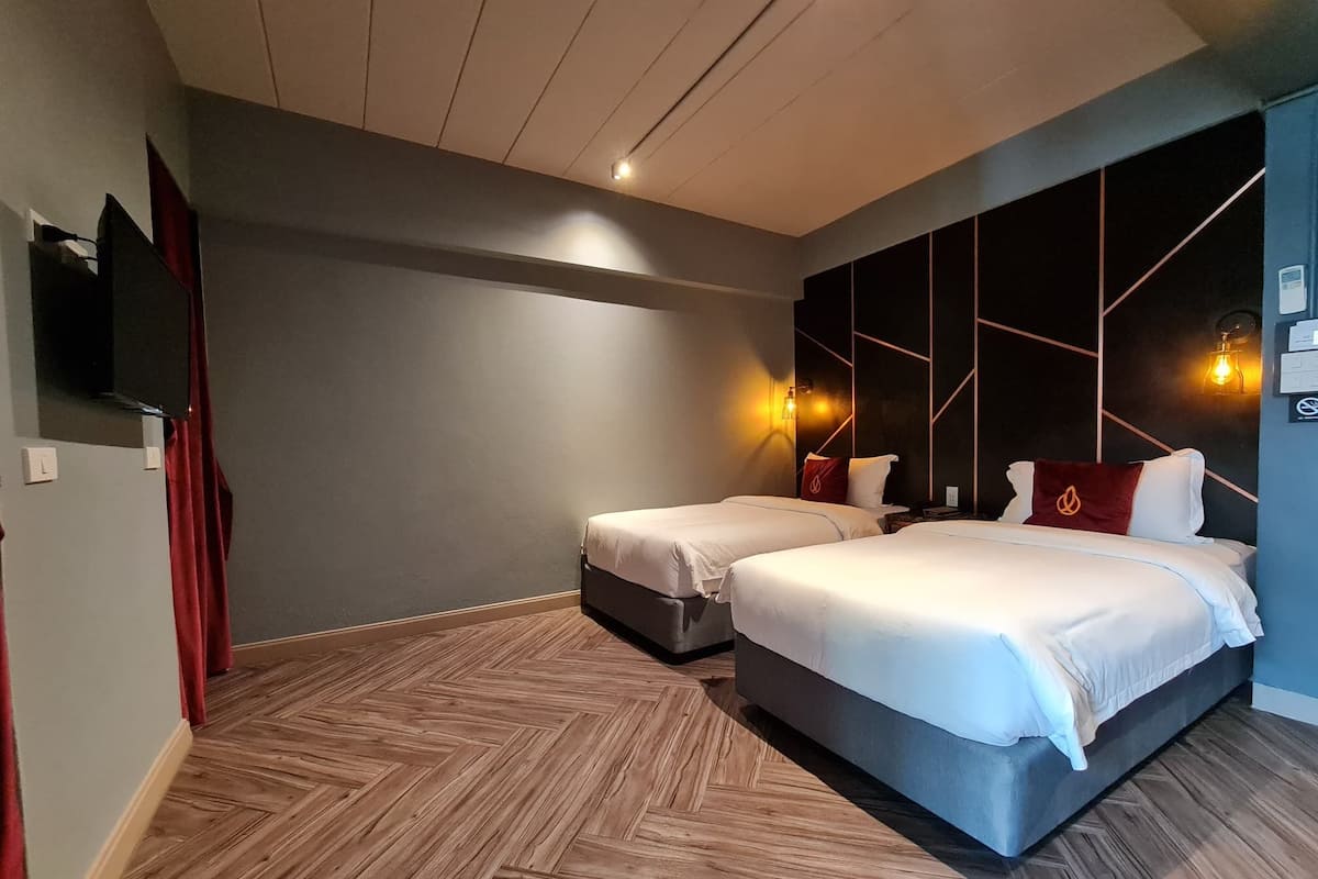 Moderni hotellihuone, jossa on kaksi sänkyä, taulutelevisio ja seinään kiinnitetty valaisin.