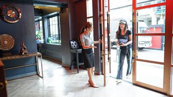 A hotel lobby with a large wooden door, a reception desk, and a decorative wall clock.