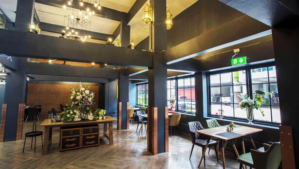 A modern interior with a wooden dining table, chairs, and a brick wall. - Ratchada Boutique Hotel (Bangkok)