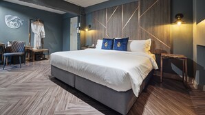 A modern bedroom with a large bed, wooden flooring, a wall-mounted headboard, and bedside lamps. - Ratchada Boutique Hotel (Bangkok)