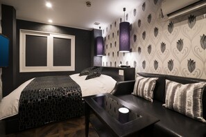 Une chambre d’hôtel moderne, équipée d’un lit, d’un canapé, d’une table basse et d’un mur recouvert d’un papier peint à motifs.