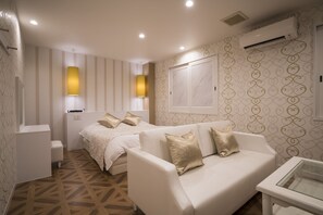 A hotel room with a bed, a sofa, a small table, and a wall-mounted air conditioner. - Hotel Xenia Amagasaki - Adult Only (Amagasaki)