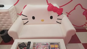 A Hello Kitty-themed chair with a cushion, a small table with remote controls and magazines, and a trash bin. - Hotel Xenia Amagasaki - Adult Only (Amagasaki)