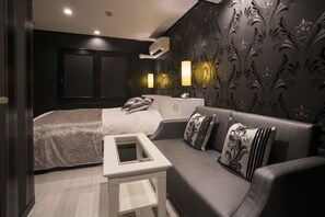 Une chambre moderne comprenant un lit, un canapé, une table de chevet et un climatiseur fixé au mur.