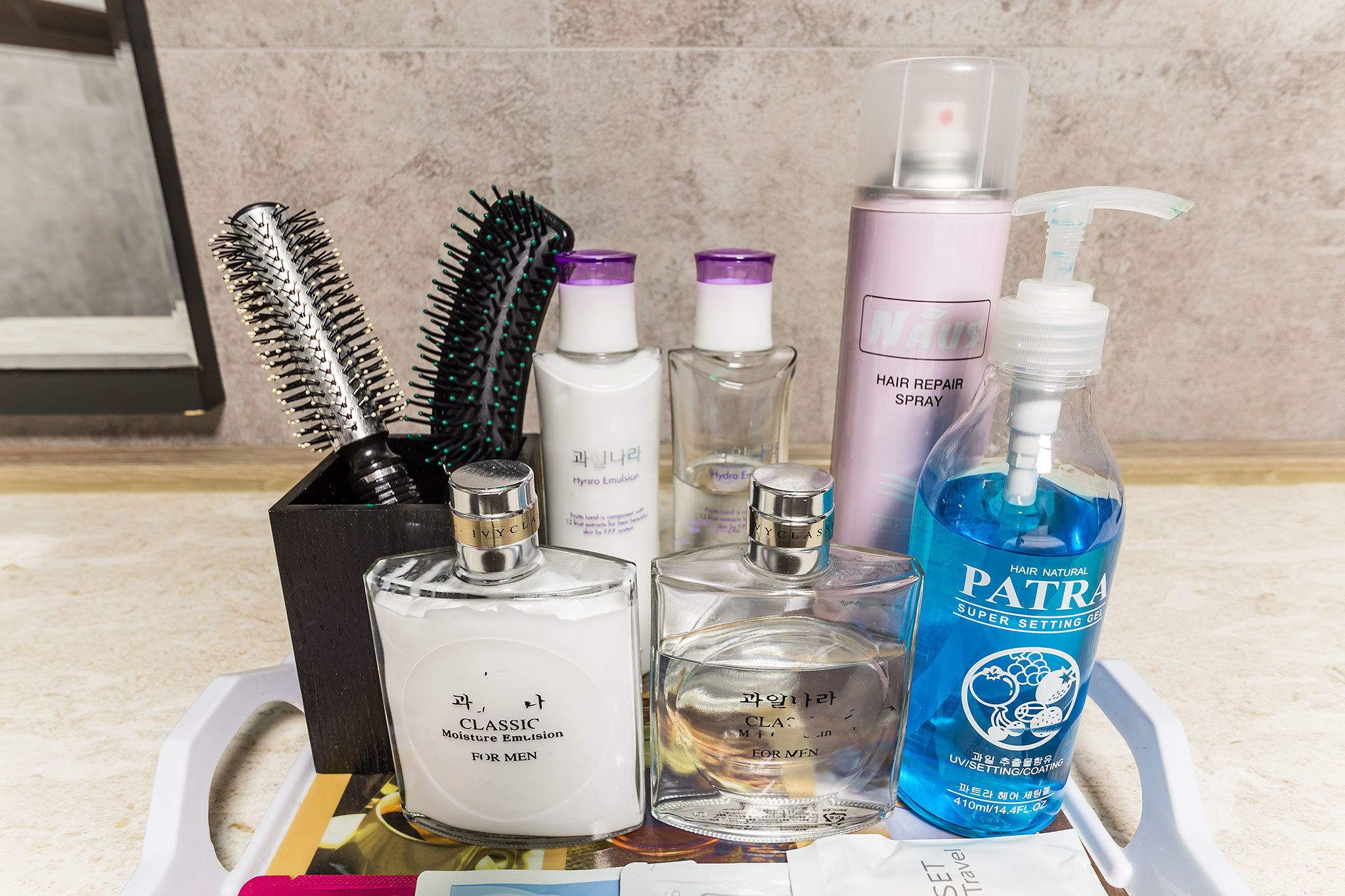 A collection of hair care products including a hairbrush, a bottle of hair repair spray, a bottle of hair setting gel, and a bottle of hair natural setting spray.