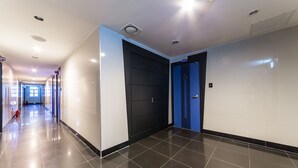 Un pasillo de hotel moderno con un suelo de baldosas brillantes, una puerta negra y una azul.