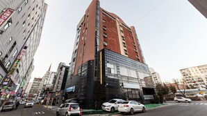 Un edificio de varios pisos con un diseño arquitectónico moderno, que combina fachadas de vidrio y ladrillo.