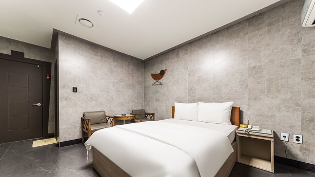 Una habitación de hotel moderna con una cama grande, un escritorio y una silla.