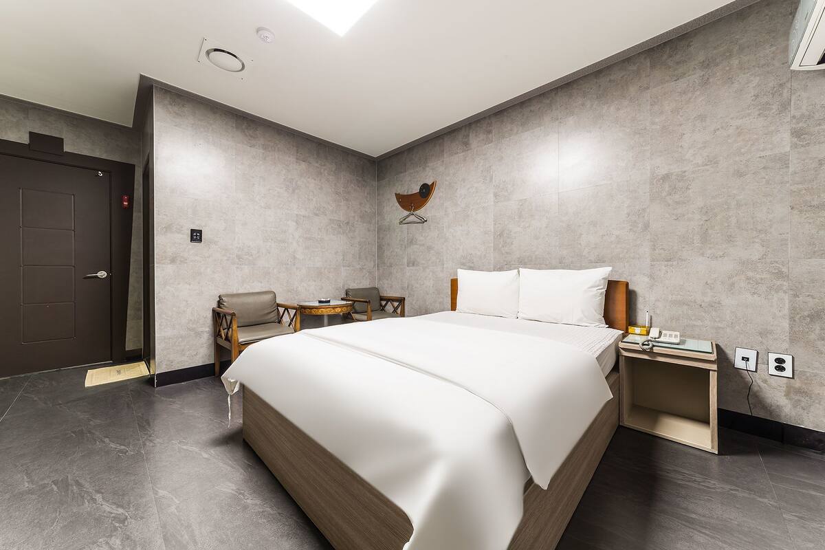 A modern hotel room with a large bed, a desk, and a chair.