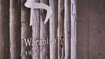 Una estructura de madera con tablones verticales y el contorno blanco de una persona. Se lee el texto 'Warabino YUFUIN'.