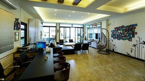 A modern office space with a long table, chairs, a sofa, a hanging chair, and a wall with framed pictures. - Mulu-Hotel (Magong)