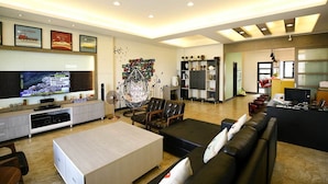 A modern living room with a TV, sofa, and a unique hanging chair. - Mulu-Hotel (Magong)