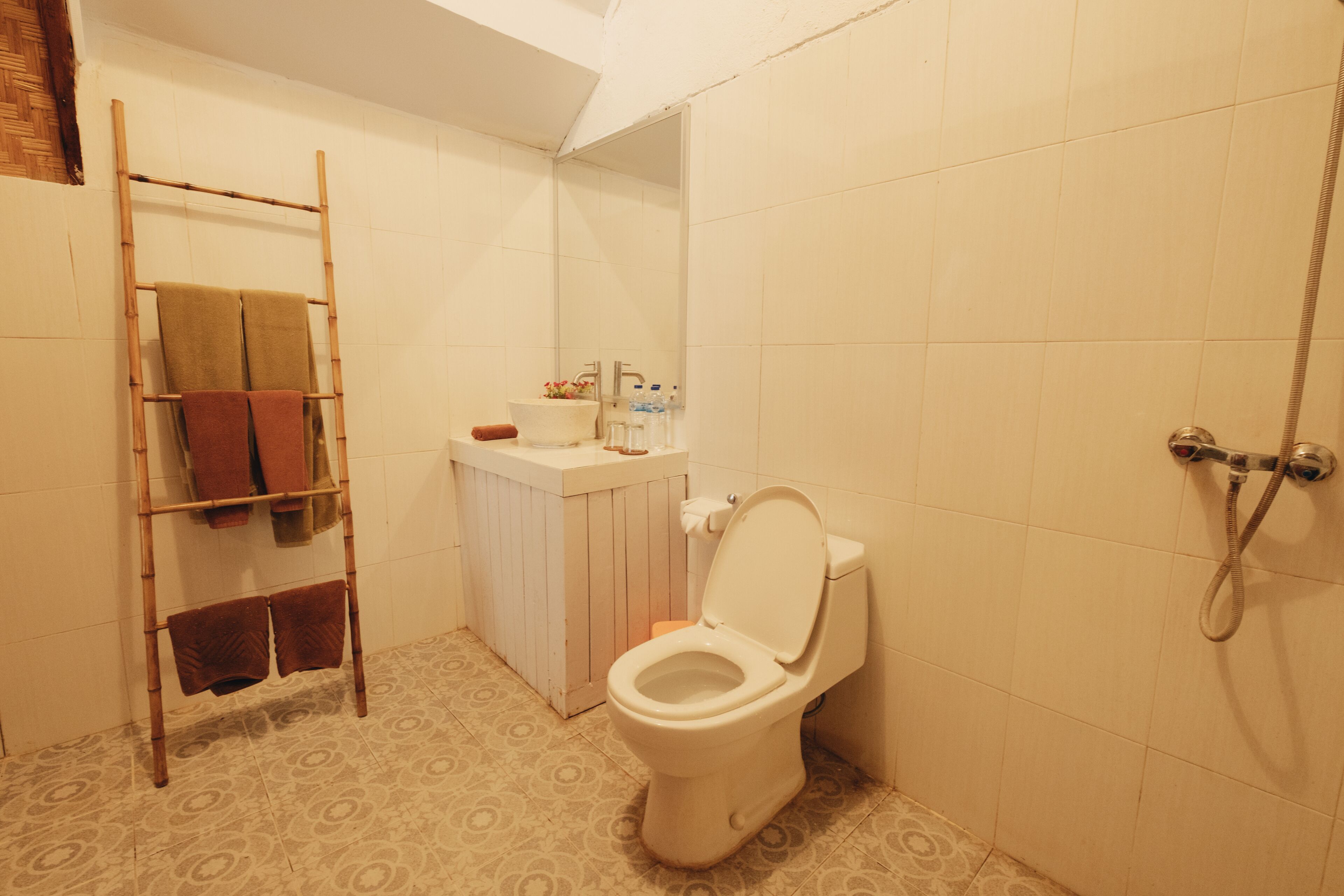 A bathroom with a toilet, a sink, a shower, and a towel rack with towels.