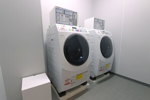 Two front-loading washing machines in a laundry room with control panels and safety instructions. -  ARIGATO STAY KANAZAWA (Kanazawa)