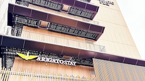 Un immeuble à plusieurs étages, doté de balcons et d’une enseigne indiquant « Arigato Stay ».