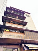 Un edificio de varios pisos con balcones y un letrero que dice 'Arigato Stay'.