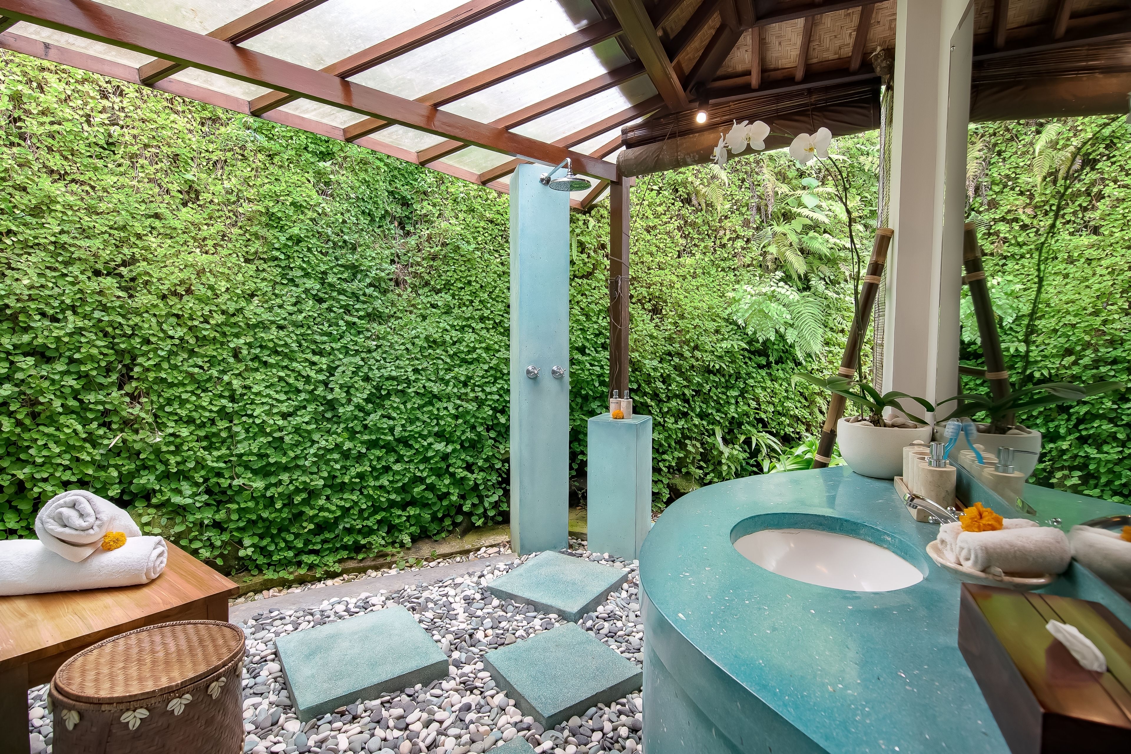 A bathroom with a large sink, a wooden bench, and a green wall.