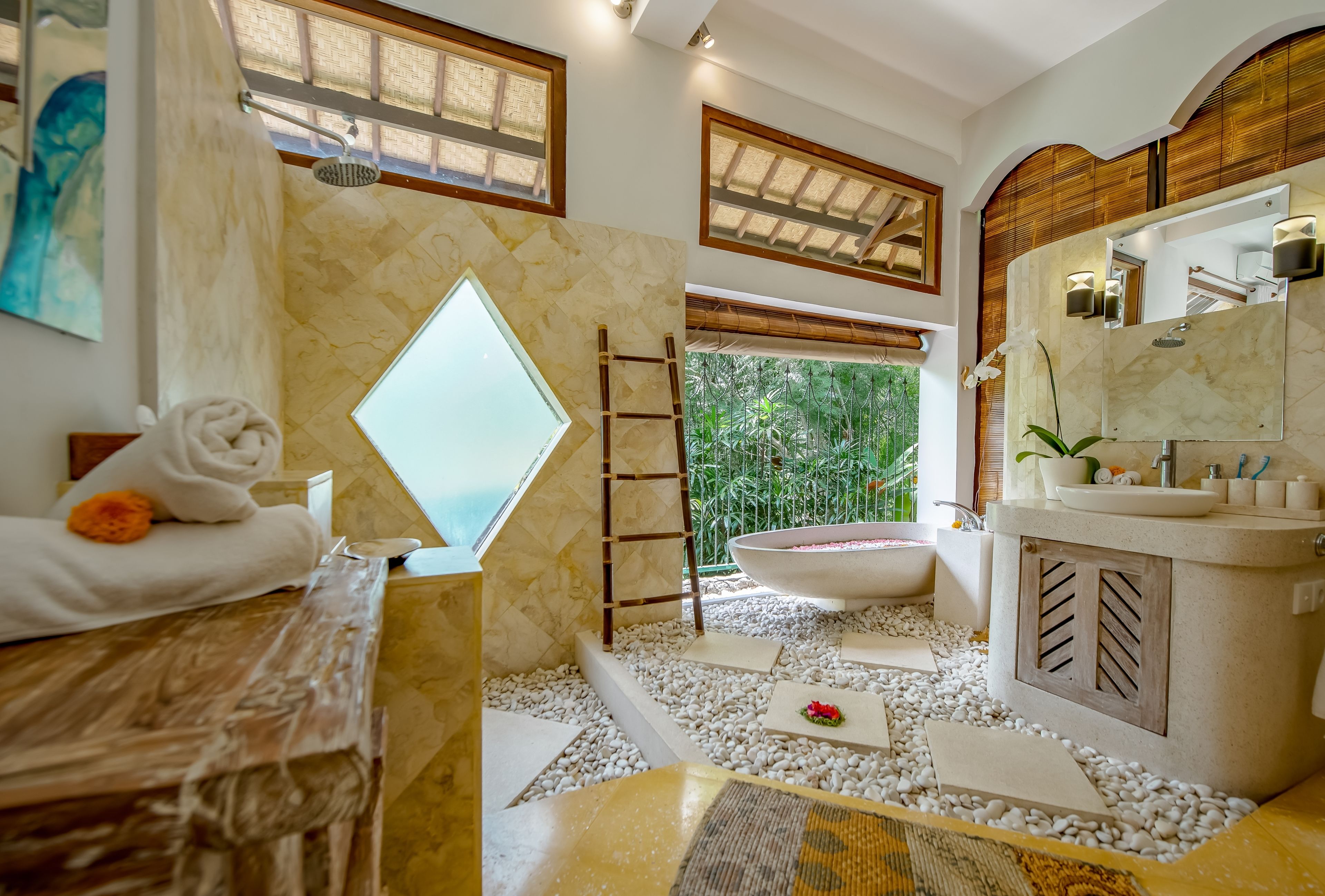 A modern bathroom with a bathtub, a large mirror, and a window overlooking greenery.