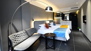 A modern hotel room with a large bed, a desk, a chair, and a small table. - Dreamhouse (Hangzhou)