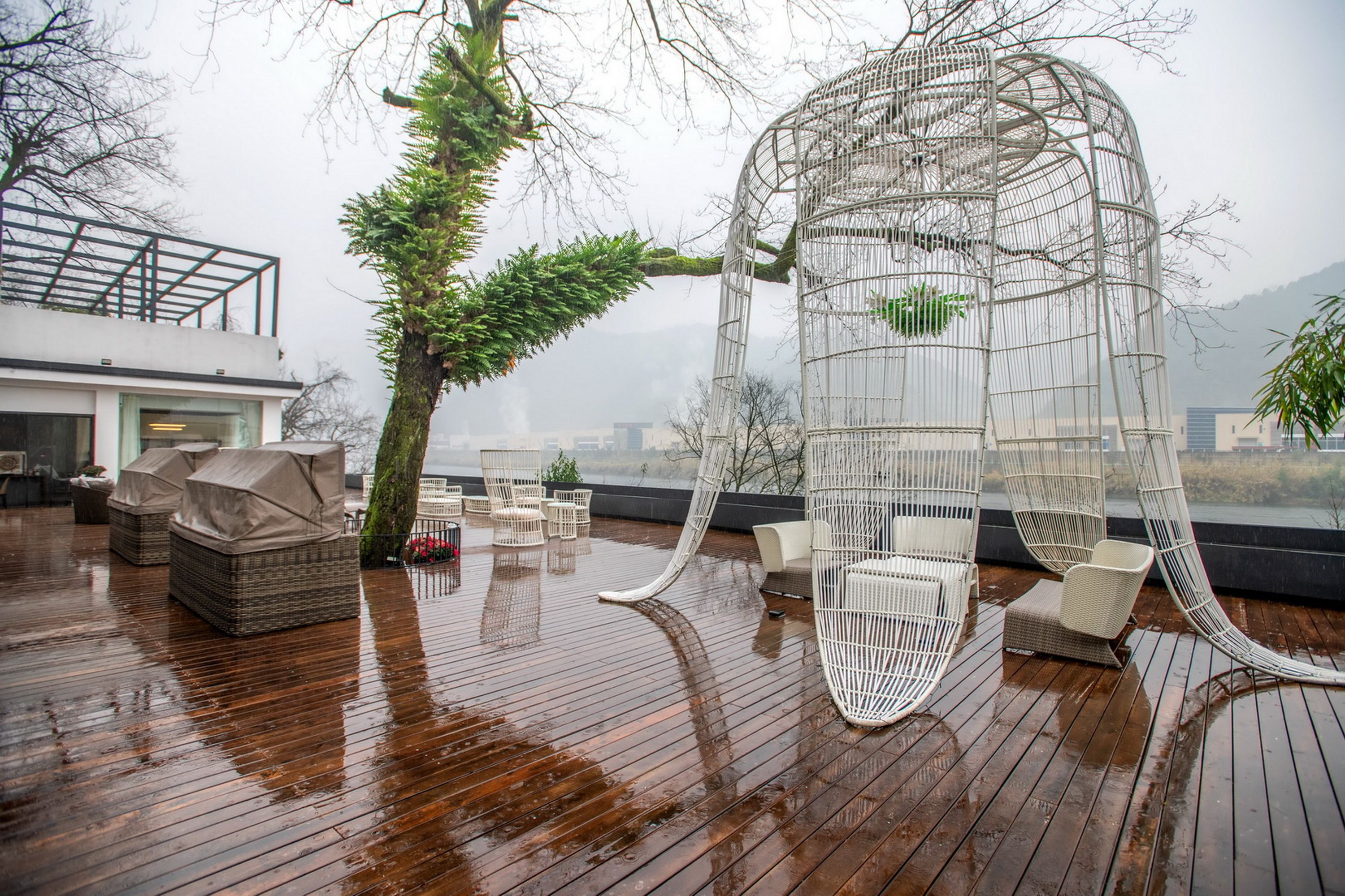 A wooden deck with wicker furniture and a white metal structure.