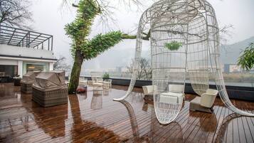 A wooden deck with wicker furniture and a white metal structure.