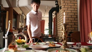 A dining table set with plates of food, a candle, and a person standing in the background. - Piccolo Hotel Opera Karuizawa (Karuizawa)