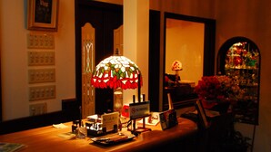 A reception desk with a stained glass lamp, a no-smoking sign, and a flower vase. - Piccolo Hotel Opera Karuizawa (Karuizawa)