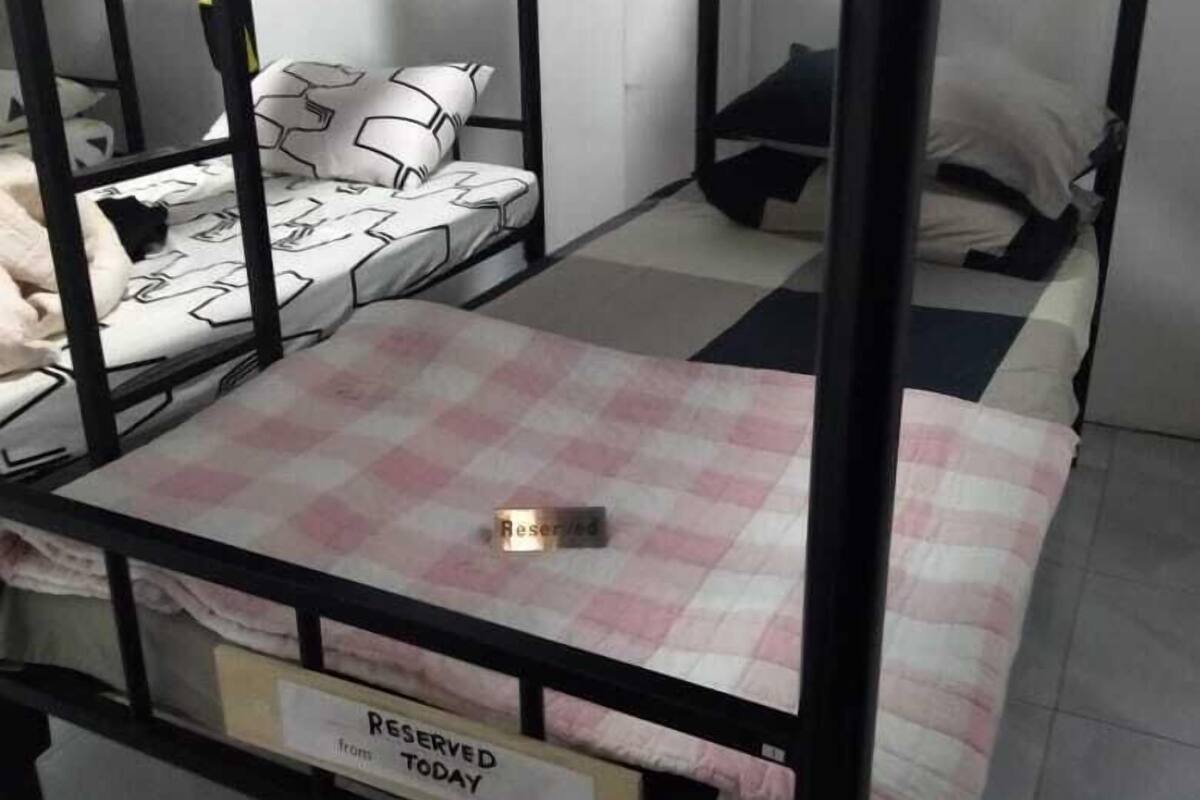 A bunk bed room with a 'Reserved Today' sign, checkered bedding, and a small table in the center.