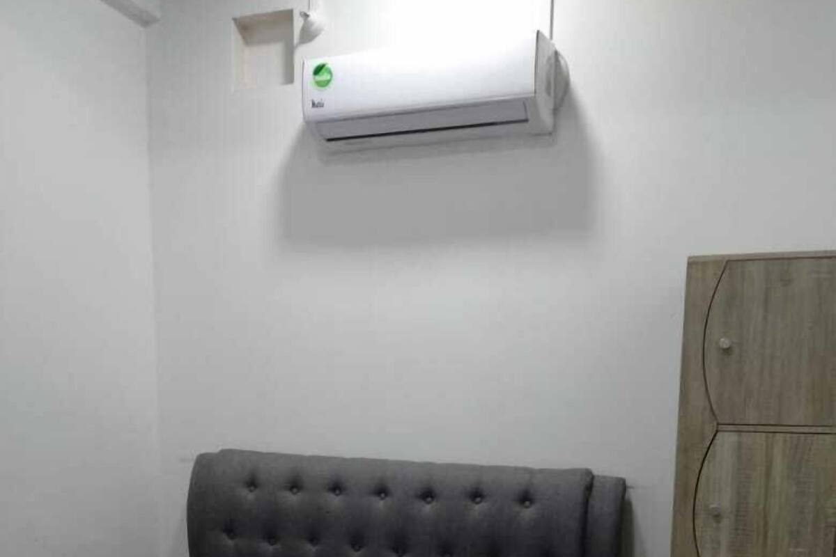A bedroom with a bed, a wardrobe, and an air conditioning unit.