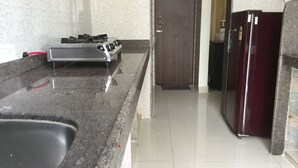 A kitchen with a granite countertop, a stainless steel stove, a sink, and a refrigerator. - Arista Service Apartments Ghansoli (Navi Mumbai)