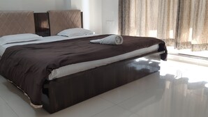 A modern hotel room with a large bed, dark wooden headboard, and a neatly made bed with a brown cover. - Arista Service Apartments Ghansoli (Navi Mumbai)