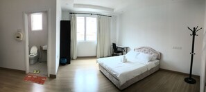 A bedroom with a bed, a desk, a chair, a coat rack, and a bathroom with a toilet and sink. - Island Hostel Bayan Lepas Airport (George Town)