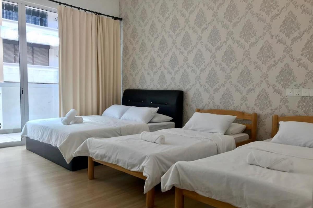 Una camera d'albergo con due letti singoli, una grande finestra con tende e carta da parati decorata.