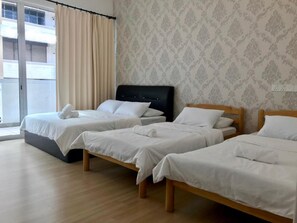 A hotel room with two single beds, a large window with curtains, and a patterned wallpaper. - Island Hostel Bayan Lepas Airport (George Town)