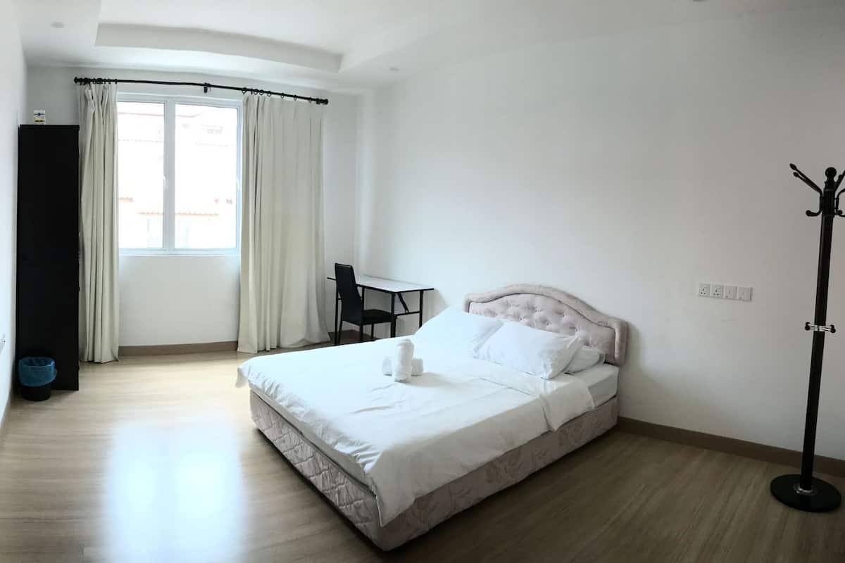 Camera da letto con un letto, una scrivania, una sedia, un appendiabiti e un bagno con il water e un lavandino.