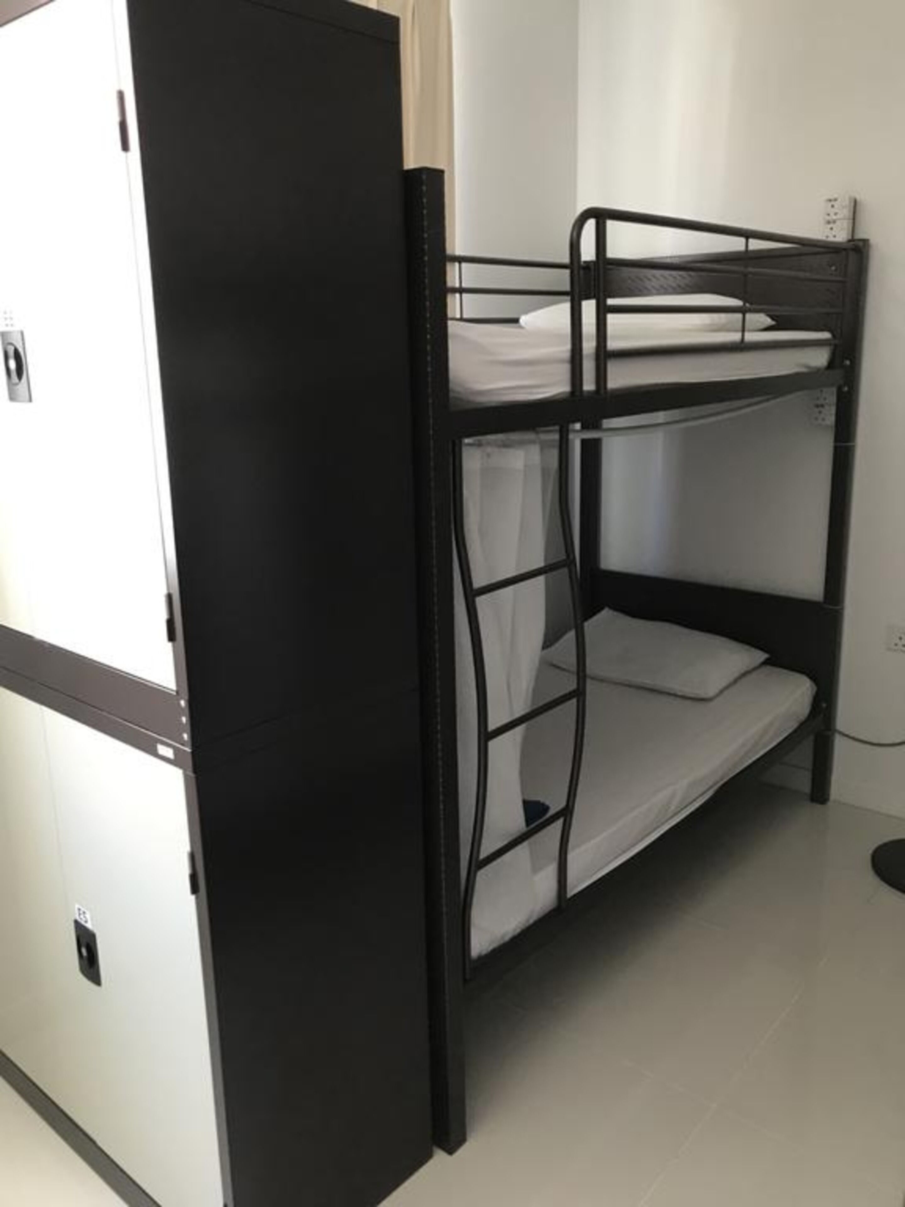 A bunk bed with a lower bunk and a top bunk, a white wardrobe, and a white door.