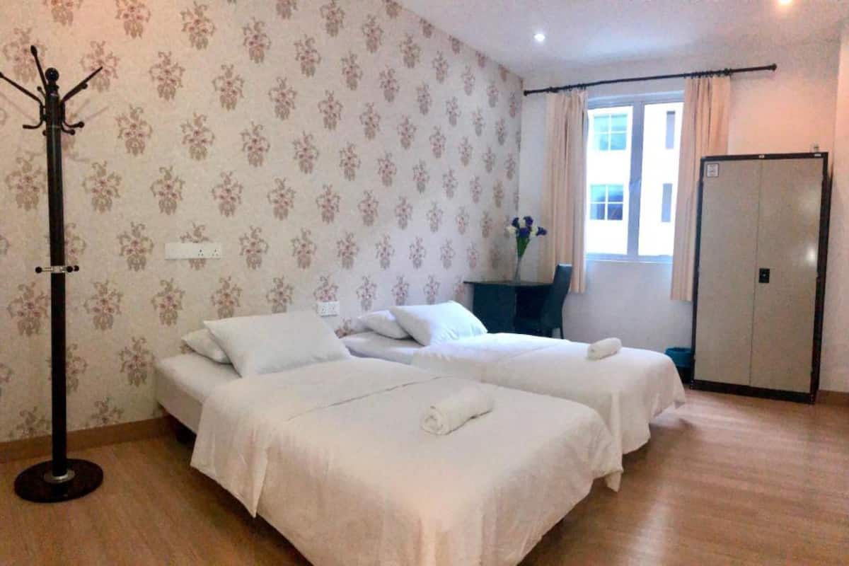 Camera d'albergo con due letti, un appendiabiti, una scrivania, una sedia e una porta.