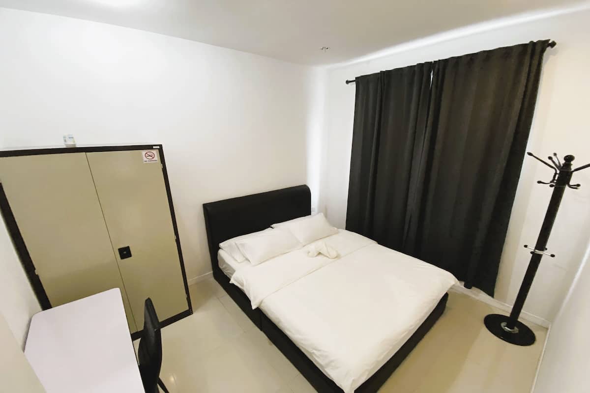 Una camera da letto con un letto, un armadio, un appendiabiti e una finestra con tende.